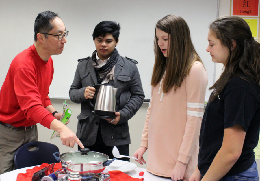 Chinese teacher Shianguu Hsieh encourages senior Liam Arciga and freshmen Kora Wiedmaier and Audrey Fulkerson to try new Chinese foods in his classroom on February 5. Photo by Mercedes Peck