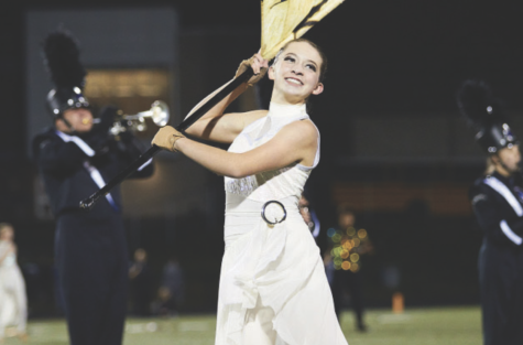    Junior Katie Wohletz waves her flag under the Friday night lights during the halftime performance. When Wohletz joined the Color Guard in eighth grade she gained an untouchable love for the sport. “Color Guard means the world to me, I love it. We call it the sport of the arts and I love it with my entire heart. So I always try to do my best in it to achieve new things I didn’t think were possible,” Wohletz said.