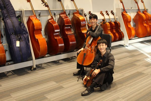 Seniors' twin brothers Michael and Matthew Fang hold a cello and a violin, as these are their preferred instruments in orchestra. Their parents encouraged them to start playing the piano at just 5 years old, and then they fell into playing the instrument they play now. “Michael pushes me and makes sure I’m being productive. If he’s practicing and I’m not, I’m like, “ I need to practice.” He keeps me accountable while still being encouraging,” Matthew Fang said. Photo by Royce Schmalz.